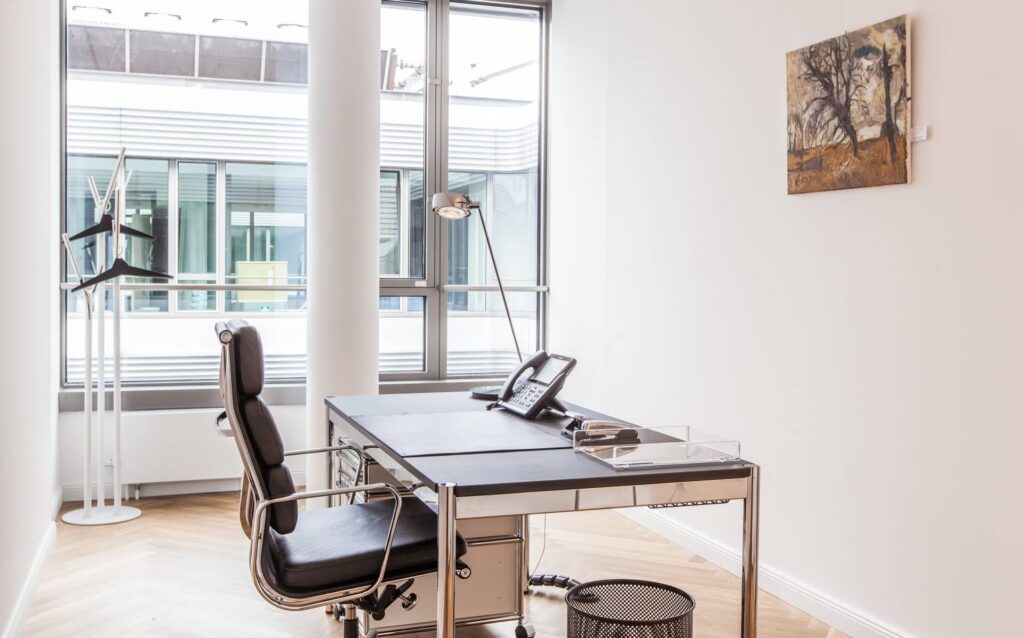 Ein helles, modern eingerichtetes Büro mit Schreibtisch, und einem großen Fenster zum Mieten im Lüneburg Kontor