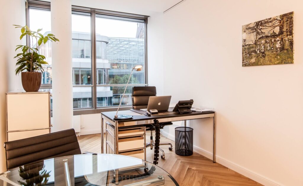 Ein helles, modern eingerichtetes Büro mit Schreibtisch, Gesprächstisch, zwei Stühlen und einem großen Fenster zum Mieten im Lüneburg Kontor